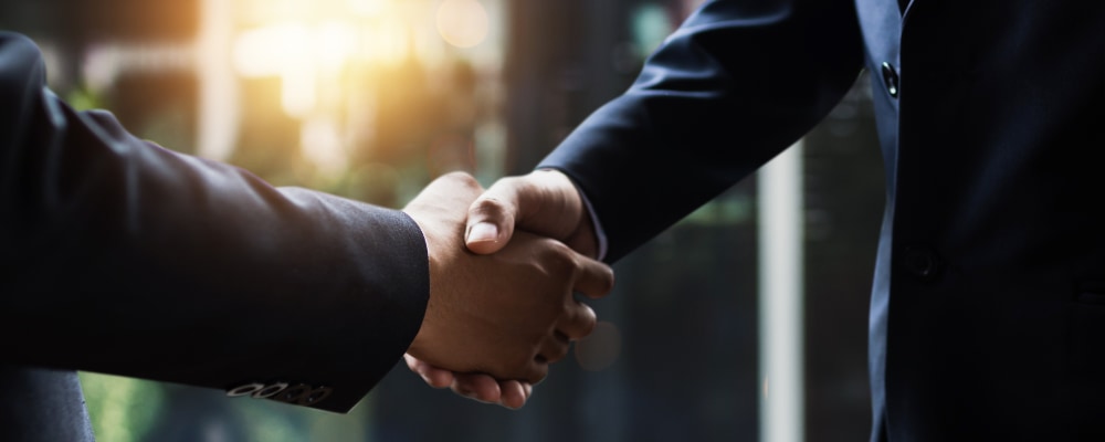  Close up of two business men in suits shaking hands