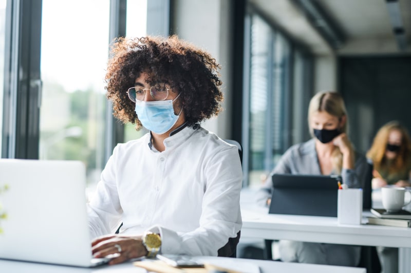 office workers sitting at desks wearing masks due to covid-19