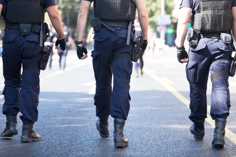 three police officers in riot gear walking down street