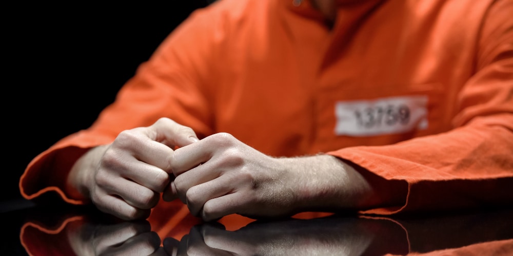 prisoner in orange uniform sitting at table