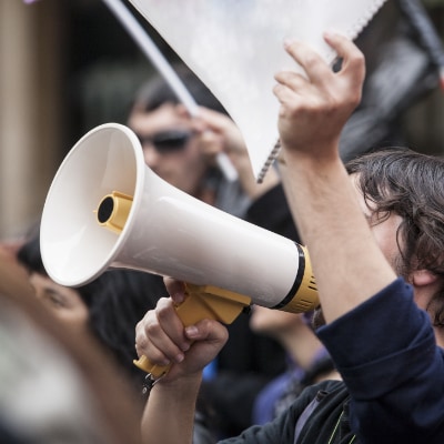 A man holding up a notepad while talking into a megaphone